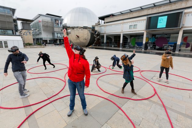 Six people wearing VR headsets and dancing in Millennium Square, Bristol