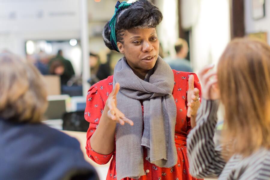 Photo of a woman standing and chatting to two other people