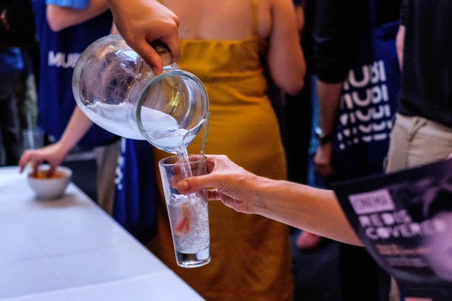 Photo of a glass of water being poured and people chatting with Mubi branded t-shirts