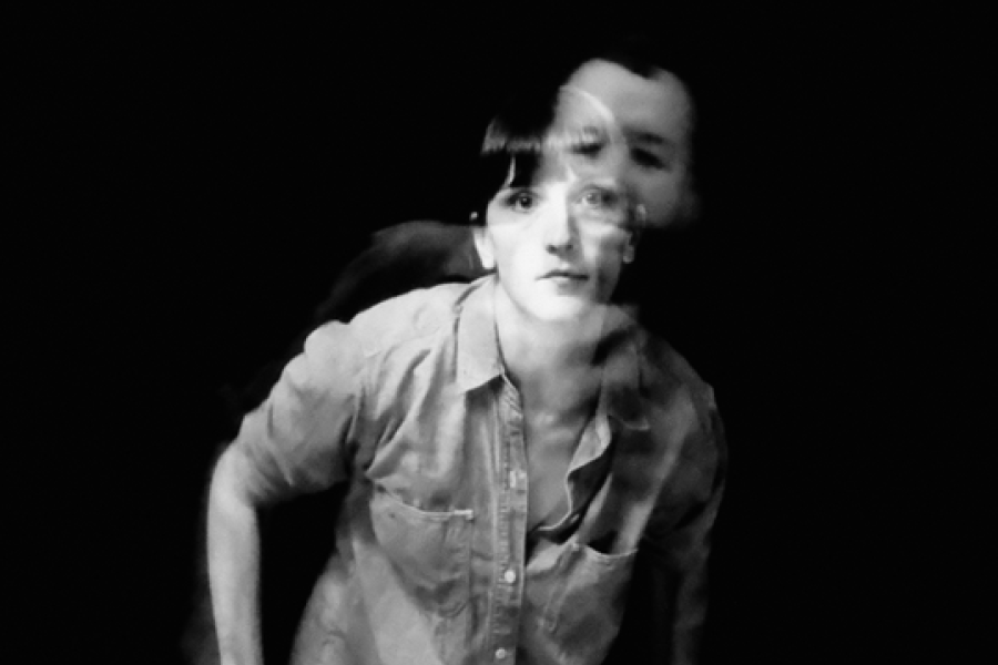 A blurry black and white photograph of a person, mid-movement