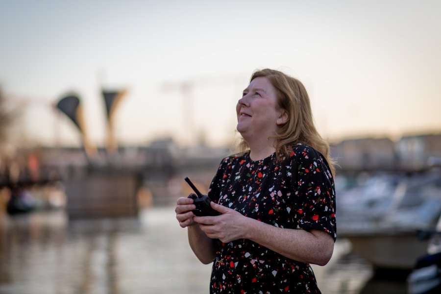 Woman holding a walkie talkie looking up at the sky