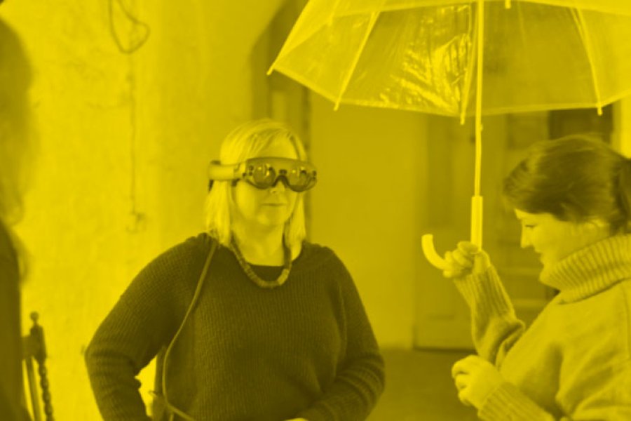 Two people one wearing a VR head set the other holding an umbrella