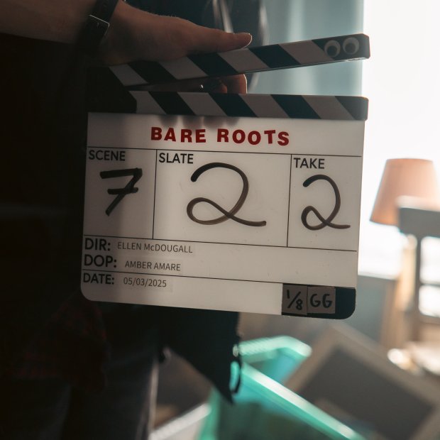 A film clapboard displaying "BARE ROOTS," scene 7, slate 22, take 2, with details for director, DOP, and date visible.