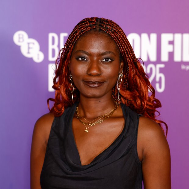 Photo of a woman with red braided hair and a black dress at a film festival against a purple and pink backdrop.