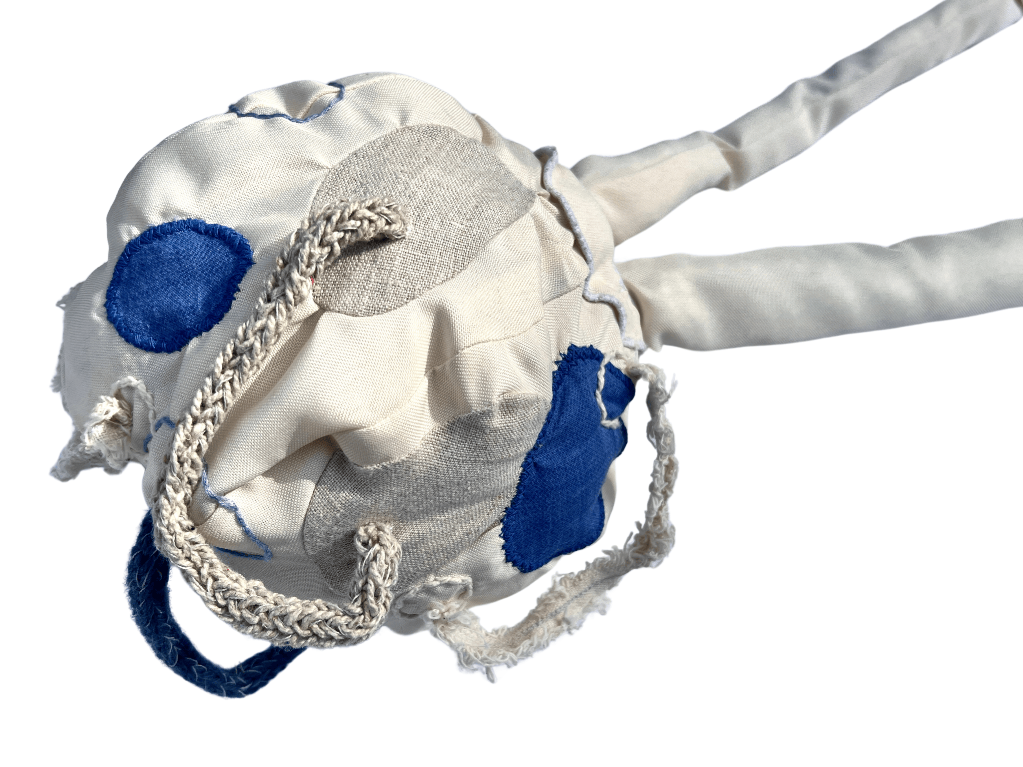 White and blue textile ball shape covered in various irregular circles in off-white and blue fabric and embroidery. It has two white tubes coming from the top off to the right of the image