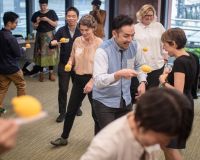 Several people playing together in a room, with lemons balanced on sticks