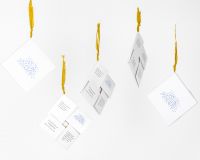 Five booklets of A Crash Course in Cloudspotting hang from yellow cords of material in the style of Literature de Cordel. The booklets are white with blue text or designs in their centre.