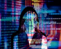 Image of a women with multi-coloured projections of coding over her