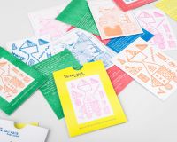 Colourful 'We Can Make Chat Show' riso prints spread out on the table in colours of green and orange, yellow and pink, orange and white, blue and white, and red.
