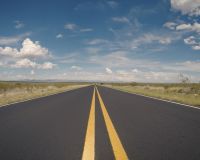 Image of a road with two yellow painted lines running through the centre. 