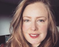 Photo of Danielle Rose, a white woman in her late thirties, strawberry blonde hair, blue grey eyes, smiling face