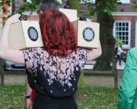 Verity holding two speaker boxes from Duncan Speakman's 'A Folded Path' up to her ears