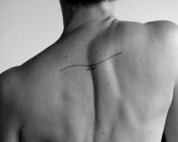 Naked top of back with a tattooed symbol across the spine