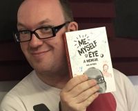 a white man with glasses holding up a paperback book: "Me, Myself & Eye: A Memoir"