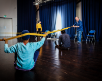 Photo of somar rehearsals - dancers can be seen holding a long stretchy band