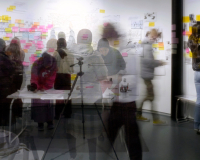 Research students gather in front of their project wall at the PHD research event.