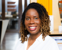 An image of a broadly smiling black businesswoman with excellent hair in a white shirt.