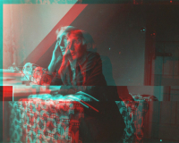 A black and white image of a Virgina Wolfe staring, deep in thought out of the window, they sit on an armchair with a bold print. The image glitches and is distorted in red and blue