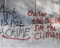 Graffiti on a grey wall, reading "art is not a crime, change the culture, not the climate"