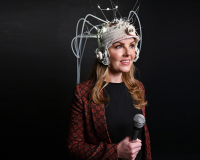 Image of Victoria Melody wearing a Faraday cage headset and holding a microphone.