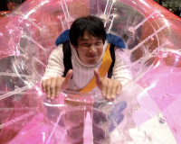 An image of a happy man, smiling at the camera and giving a thumbs up, in a large pink inflatable ring, at the Future Undokai Project. 