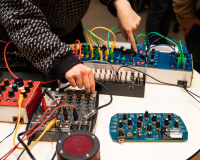 Hands turn dials on a home made synth
