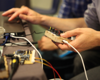 Two hands holding several bits of electronic equipment