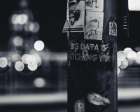 A black and white image of a lamp post with text written on it - the text reads "Big Data is Watching You", and is written on the lamp post with white ink on the black structure. 