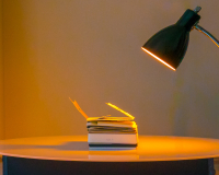 An image of Sister Sylvester's hand made book Constantinopoliad lying flat on a table, illuminated in a warm orange by a nearby desk lamp. 