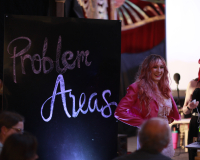 A woman stands in front of a sign reading "Problem Areas"