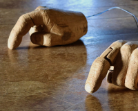 Two mechanical hands, made of wood, on a wooden table.