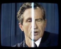 distorted image of a male with a stripe of light through the face to separate the left and the right side. The image has a blue background and black tv effect to frame the image 