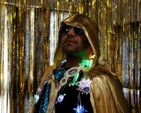 An image of Tony Bhajam, the Watershed Inclusion Officer wearing a gold cape and fairy lights around his neck, and a pair of sunglasses, looking into the distance.