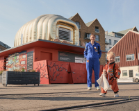 A woman and child stand in front of a golden structure 