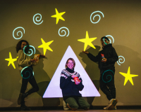 Team of three people smiling and pausing in front of colourful projected drawing