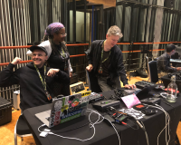 Several people sitting at audio works stations surrounded by audio equipment in Real World's Recording Studio.