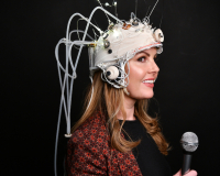 Image of Victoria Melody wearing a Faraday cage headset and holding a microphone.