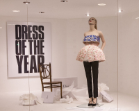 Mannequin dressed in embroidered top and short balloon skirt, propped up in window display.