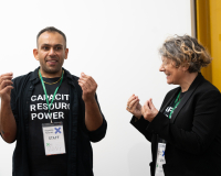 Two people wearing 'Capacity, Resource, Power' t-shirts are presenting work.