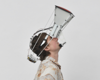 A person wearing a large projector-like device strapped to their face, gazes up.