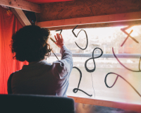 A person places their hand on a window with a set of numbers painted on it.