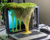 A laptop with green slime moold oozing onto the keboard.