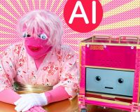 A person sitting at a gold desk in front of a gold and pink sunburst pattern. They are wearing a knitted pink mask with big google eyes, a pink wig, a pink kimono with gold obi, and one white cotton glove. Next to them is DoxBox, a hot pink robot on wheels with an animated face on a screen.