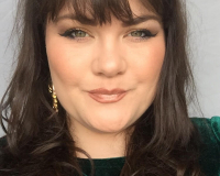 this image show scarlett smyth, wearing a green velvet dress, a woman, smiling into the camera.