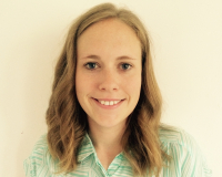 Photo of Rachael, a white woman with dar blonde wavy hair. Rachael is wearing a green and white shirt and standing against a white background.