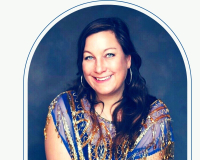 A head and shoulders shot of Caroline who is smiling facing the camera, she has brown hair and a blue and gold sparkly top. 