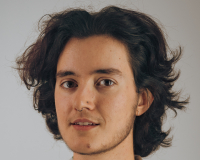 A person in their late 20s with brown hair, short stubble and a shirt with a leaf pattern.