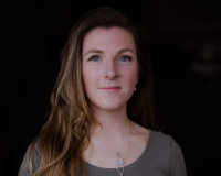 Portrait of Hannah Southfield, a person with long hair and a grey top against a dark background