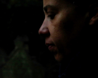 Profile of a human face, brown against shadows, contemplative, looking down