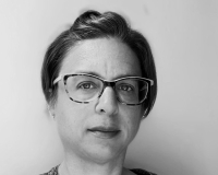 A black and white photograph of a white woman in her 40s with short hair and glasses